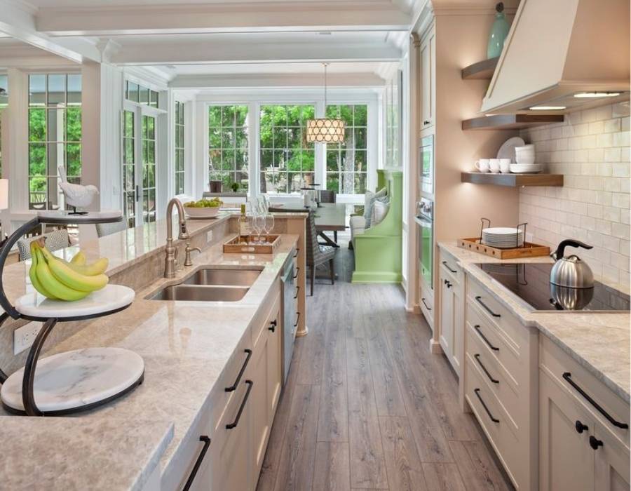 Elegant Lowcountry kitchen design with marble countertops, open shelving, light cabinetry, and a cozy built-in dining nook by Group 3 Designs.